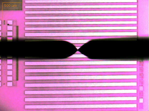 Stylus profiler tip contacting a patterned test structure under microscope magnification